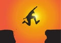 Silhouette of man jumping over the cliffs on golden sunrise background, achievement, success and winning concept