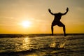 silhouette of a man in a jumping position In the sea at sunse