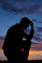 Silhouette of man kneel in sunset hand on head