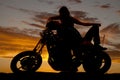 Silhouette man lay back on motorcycle woman over him