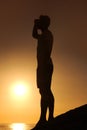 Silhouette, man or looking with hands for view, scenery and wellness on beach with sunset and peace. Person, shadow or Royalty Free Stock Photo