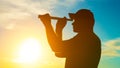 A silhouette of a man looking at using a monocular telescope against a dramatic sky at sunset. business idea concept, look to the