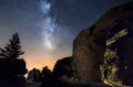 Silhouette of a man in the night exploring a cave in the mountain with a torch under an amazing the milky way