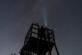 Silhouette of a man on an observation tower in Estonia shining a flashlight at the clear starry night sky Royalty Free Stock Photo