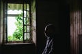 Silhouette of a man in an old uninhabitable house in front of a window. Depression, loneliness, despair, decline, sadness concept Royalty Free Stock Photo