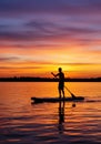Silhouette of a Man Paddleboarding at Sunset on a Calm Lake Royalty Free Stock Photo
