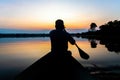 Silhouette of a man paddling canoe at dusk calm water Royalty Free Stock Photo
