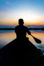 Silhouette of a man paddling canoe at dusk calm water Royalty Free Stock Photo