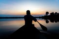 Silhouette of a man paddling canoe at dusk calm water Royalty Free Stock Photo