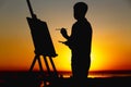 Silhouette of a man painting a picture with paints on canvas on an easel on nature, boy with paint brush and palette engaged in ar Royalty Free Stock Photo