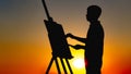 Silhouette of a man painting a picture with paints on canvas on an easel on nature, boy with paint brush and palette engaged in ar Royalty Free Stock Photo