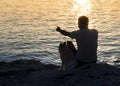 Silhouette of man pointing into the distance and dog sitting together at the seaside and looking at the sunrise Royalty Free Stock Photo