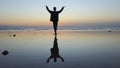 Silhouette of man practiceing qigong exercises at sunset by the sea