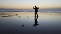 Silhouette of man practiceing qigong exercises at sunset by the sea