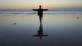 Silhouette of man practiceing qigong exercises at sunset by the sea