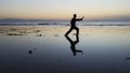 Silhouette of man practiceing qigong exercises at sunset by the sea