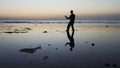 Silhouette of man practiceing qigong exercises at sunset by the sea