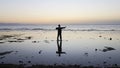 Silhouette of man practiceing qigong exercises at sunset by the sea.