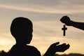 Silhouette of a man praying with a cross in hand at sunrise,  religion concept Royalty Free Stock Photo