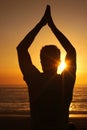 Silhouette, man and praying with hands for yoga, health and wellness on beach with sunset and zen. Person, shadow and