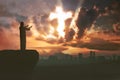 Silhouette of man praying to god with ray of light shaping cross