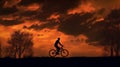 Silhouette of man riding bike with orange cloudy sunset
