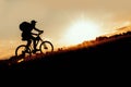Silhouette of a man riding a bike uphill at sunset Royalty Free Stock Photo