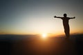 Silhouette of man rise hand up praying  on top of mountain and sunset sky abstract background. Freedom and travel adventure Royalty Free Stock Photo