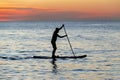 Silhouette of man is rowing on a SUP board against background of sunset sky. Standing paddleboarding Royalty Free Stock Photo