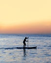 Silhouette of man is rowing on a SUP board against background of sunset sky. Standing paddleboarding Royalty Free Stock Photo