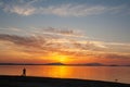 Silhouette of a man on the shore of the lake at sunset. Sunset over the sea with dramatic sky and reflection in the water Royalty Free Stock Photo