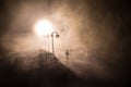 The silhouette of a man in shorts, standing in the middle of the road on a misty night. The glare of the street light against the