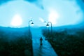 The silhouette of a man in shorts, standing in the middle of the road on a misty night. The glare of the street light against the