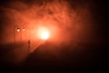 The silhouette of a man in shorts, standing in the middle of the road on a misty night. The glare of the street light against the