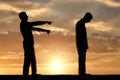 A silhouette of a man showing a finger at another man telling him that he is a loser