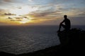 Silhouette of man rests on rock during sunrise Royalty Free Stock Photo