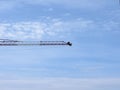 A silhouette of a man sitting at the end of a long arm of a crane