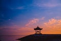 Silhouette of a man sitting in a gazebo on the beach at dawn on Sanur beach, Bali, Indonesia. A man admires the dawn Royalty Free Stock Photo