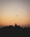 Silhouette of the man sitting on the rock with a bird flying against a sunset Royalty Free Stock Photo