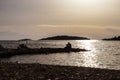 Silhouette of man sitting on the stone pier at sunset, watching the sea and distant islands, photographed at the Rogoznica town Royalty Free Stock Photo