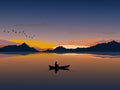 Silhouette of a man on a small boat that is fishing There is  mountain and  sunset background Royalty Free Stock Photo