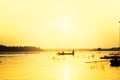 Silhouette man in small fishing boat at lake with mountain view against sunset sky Royalty Free Stock Photo