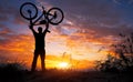 Silhouette the man stand in action lifting bicycle above his head Royalty Free Stock Photo