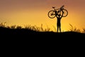 Silhouette the man stand in action lifting bicycle above his head with sunset Royalty Free Stock Photo