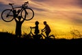 Silhouette the man stand lifting bicycle above his head with little boy and little girl riding bike on sunset Royalty Free Stock Photo