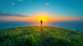 The silhouette of a man standing on a cliff by the sea against the background of the setting sun and the bright blue sky Royalty Free Stock Photo