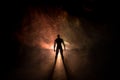 Silhouette of man standing on an dark foggy toned background. Decorated photo with man figure on table with light. Royalty Free Stock Photo