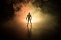 Silhouette of man standing on an dark foggy toned background. Decorated photo with man figure on table with light. Royalty Free Stock Photo