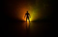 Silhouette of man standing on an dark foggy toned background. Decorated photo with man figure on table with light. Royalty Free Stock Photo