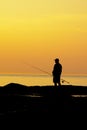 Silhouette of a man fishing in the north sea against the glow of the evening sky after sunset